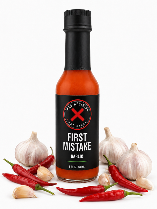 First Mistake garlic hot sauce bottle surrounded by fresh garlic