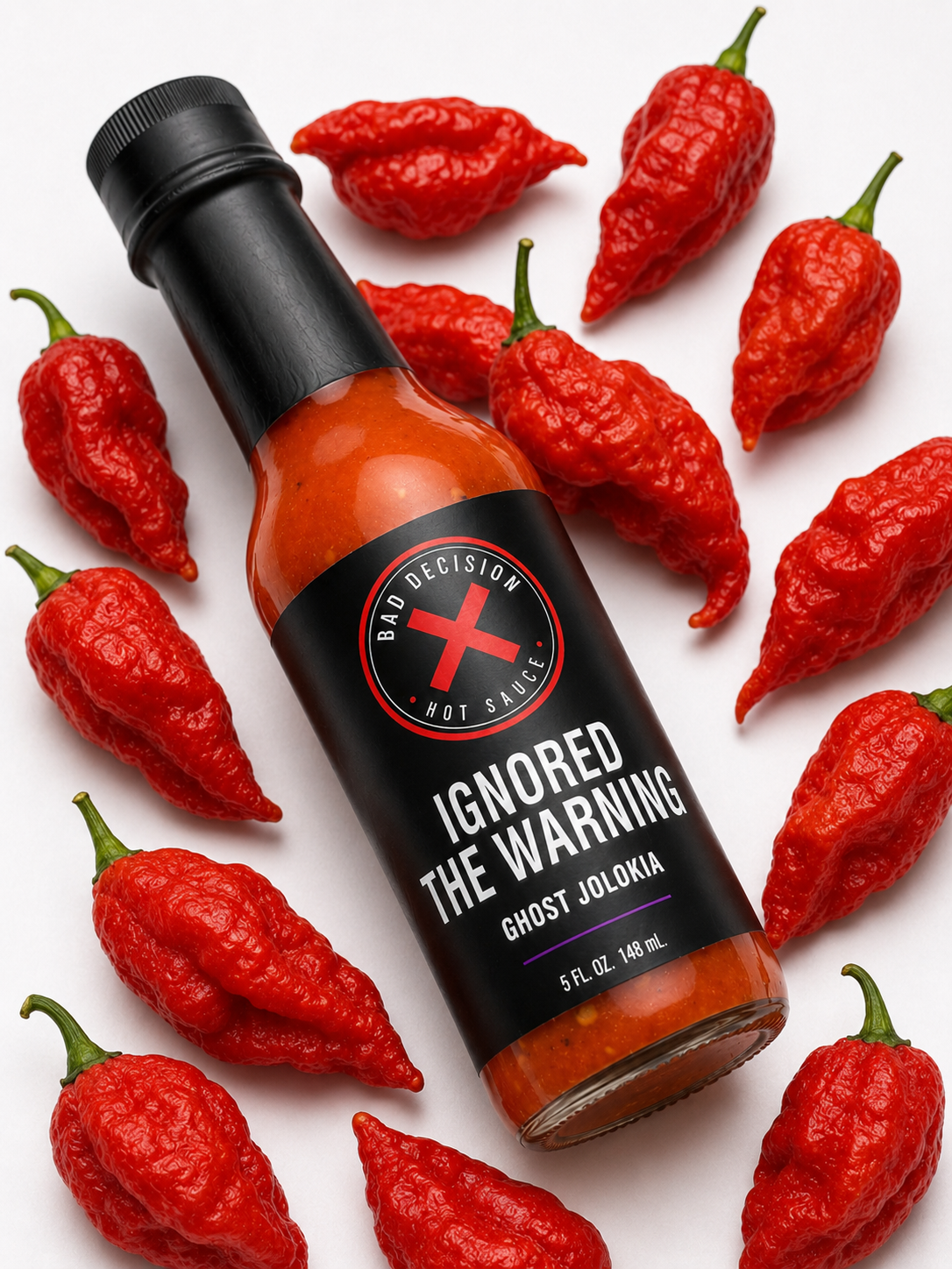 Close-up of Ignored The Warning ghost jolokia hot sauce bottle among red ghost peppers
