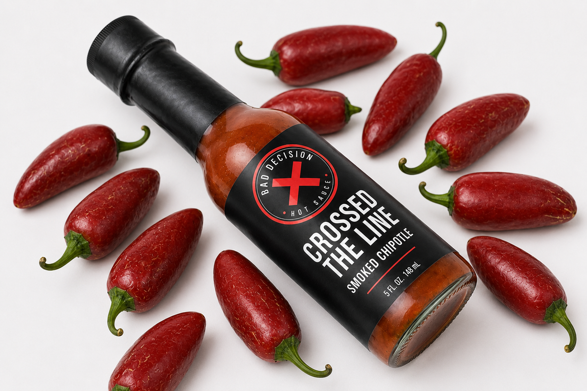 Close-up of Crossed The Line smoked chipotle hot sauce bottle among dried chipotle peppers
