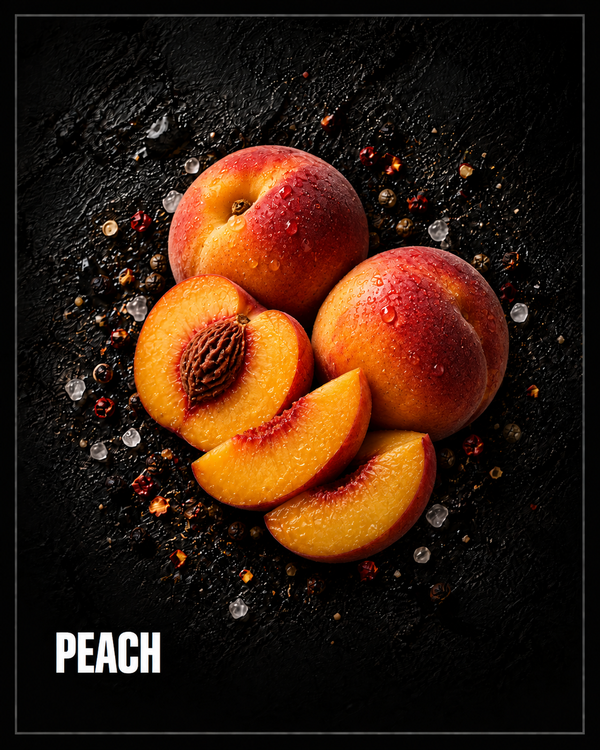 Ripe peaches, whole, halved with the stone showing and sliced, on dark stone with scattered chilli flakes and salt