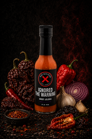 Ignored The Warning ghost jolokia hot sauce bottle with ghost peppers and ingredients on a dark background
