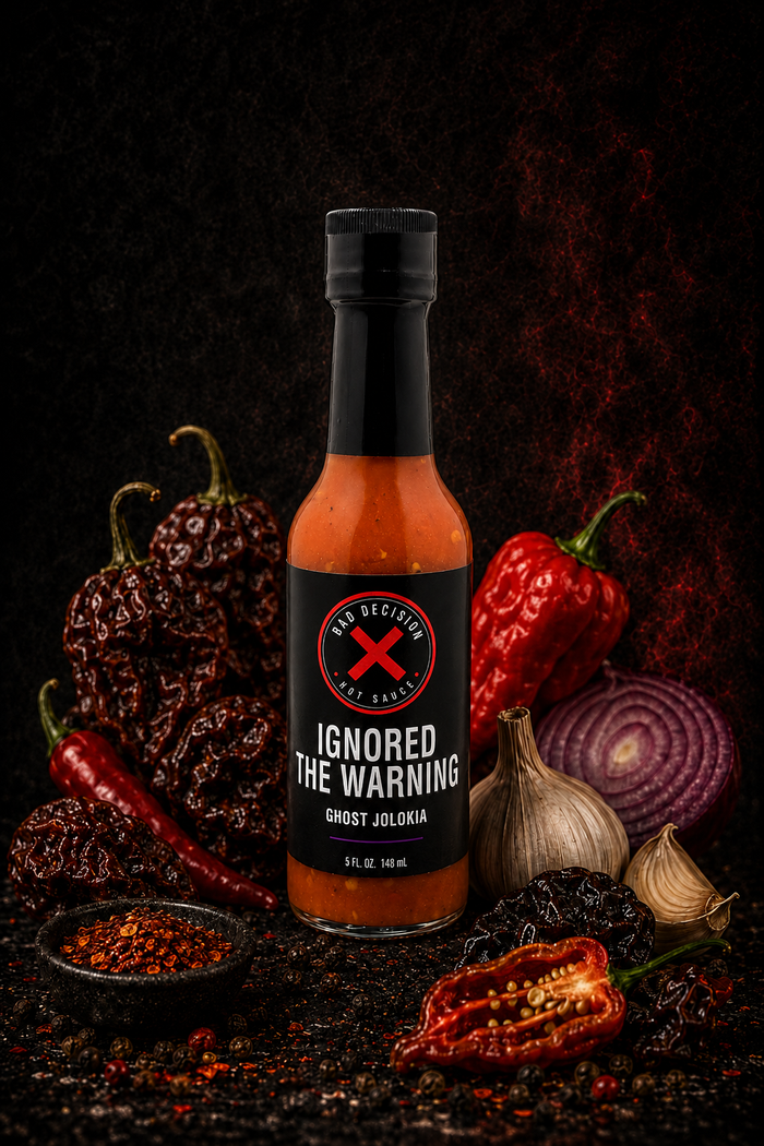 Ignored The Warning ghost jolokia hot sauce bottle with ghost peppers and ingredients on a dark background