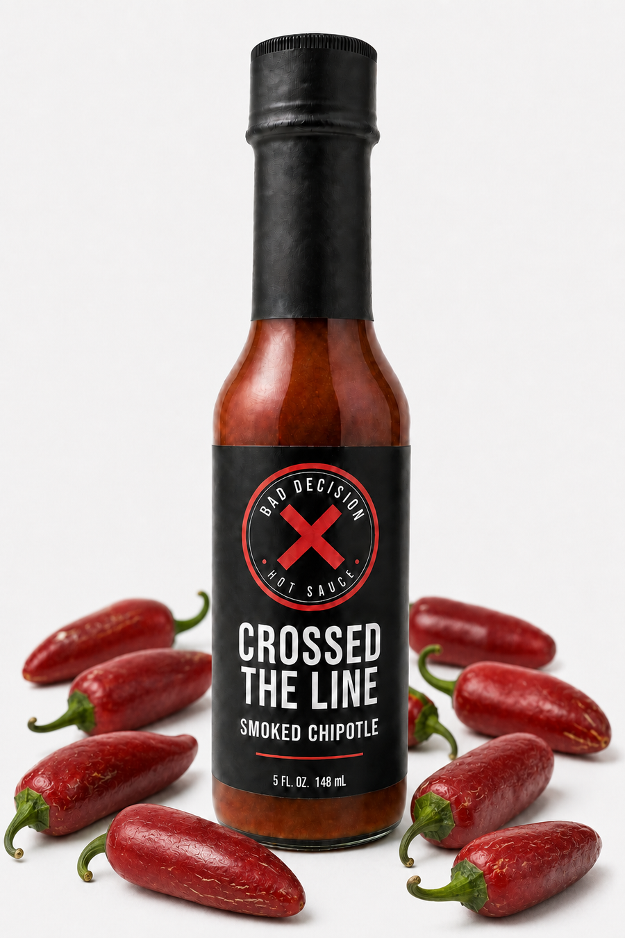 Crossed The Line smoked chipotle hot sauce bottle surrounded by dried chipotle peppers