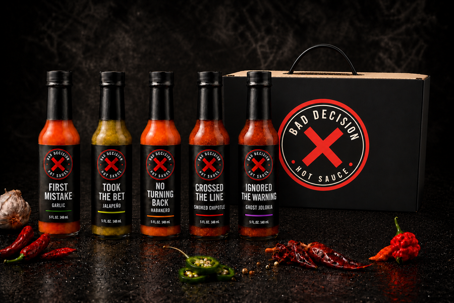 The Complete Bad Decision 5-Bottle Set — First Mistake garlic, Took The Bet jalapeño, No Turning Back habanero, Crossed The Line smoked chipotle and Ignored The Warning ghost jolokia in front of the black Bad Decision gift box
