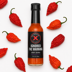 Ignored The Warning ghost jolokia hot sauce bottle lying among red ghost peppers