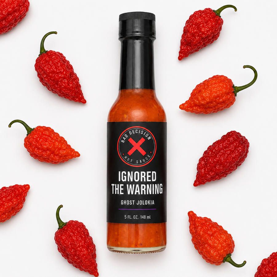 Ignored The Warning ghost jolokia hot sauce bottle lying among red ghost peppers