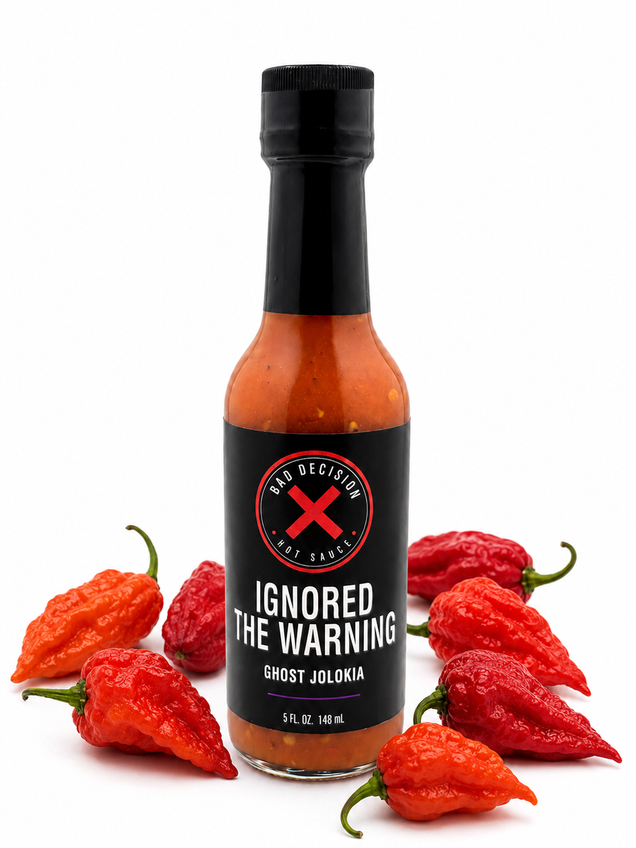 Ignored The Warning ghost jolokia hot sauce bottle surrounded by red ghost peppers