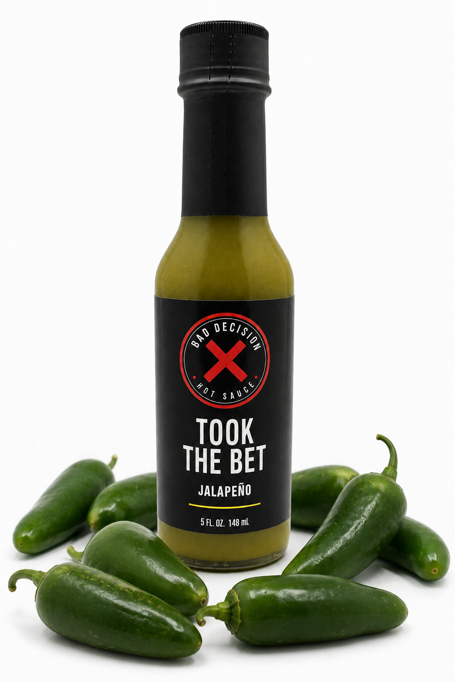 Took The Bet jalapeño hot sauce bottle surrounded by fresh jalapeño peppers