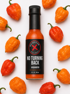 Close-up of No Turning Back habanero hot sauce bottle among fresh habanero peppers
